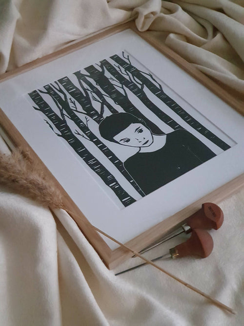 Affiche encadrée en bois clair : portrait féminin et forêt de traits noirs