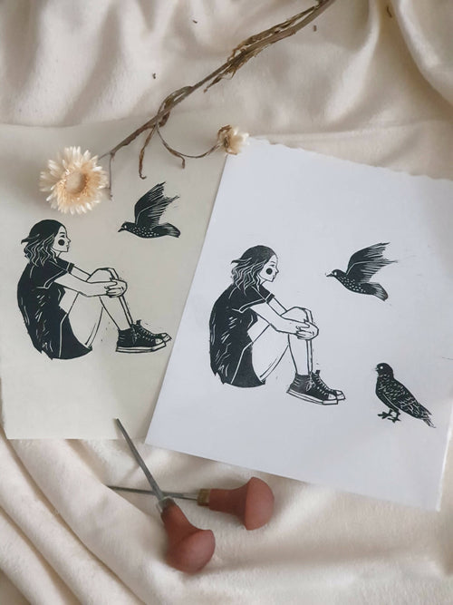 Deux affiches papier avec jeune fille et oiseaux noirs, vues de côté