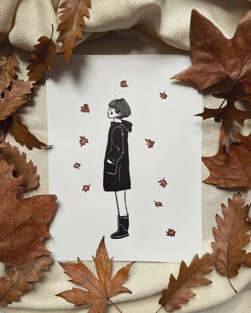 Impression sur papier blanc : silhouette féminine noire avec étoiles rouges, décor automnal.