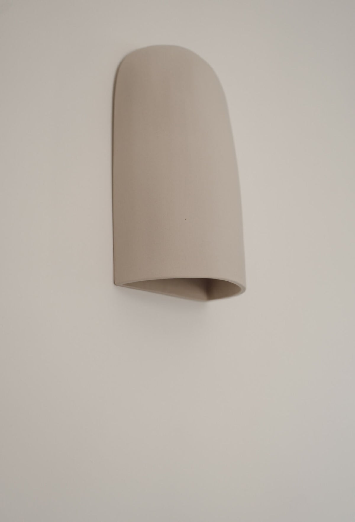 Applique murale beige en céramique, abat-jour courbé, angle légèrement décalé.