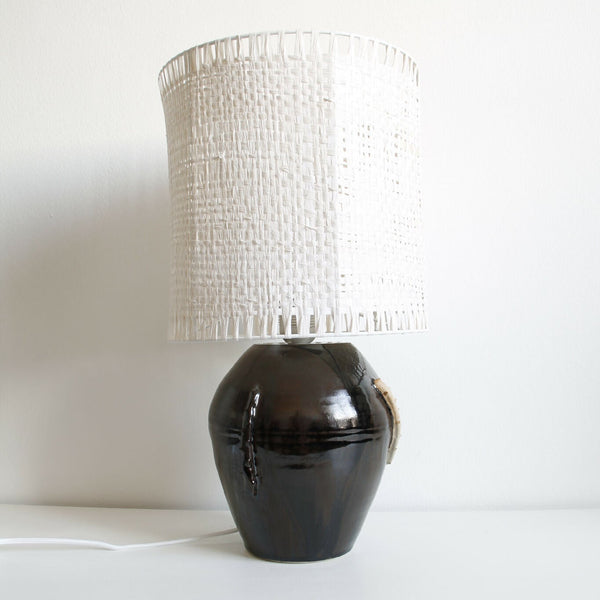 Lampe Puntia avec base noire brillante et abat-jour cylindrique en tissu blanc ajouré