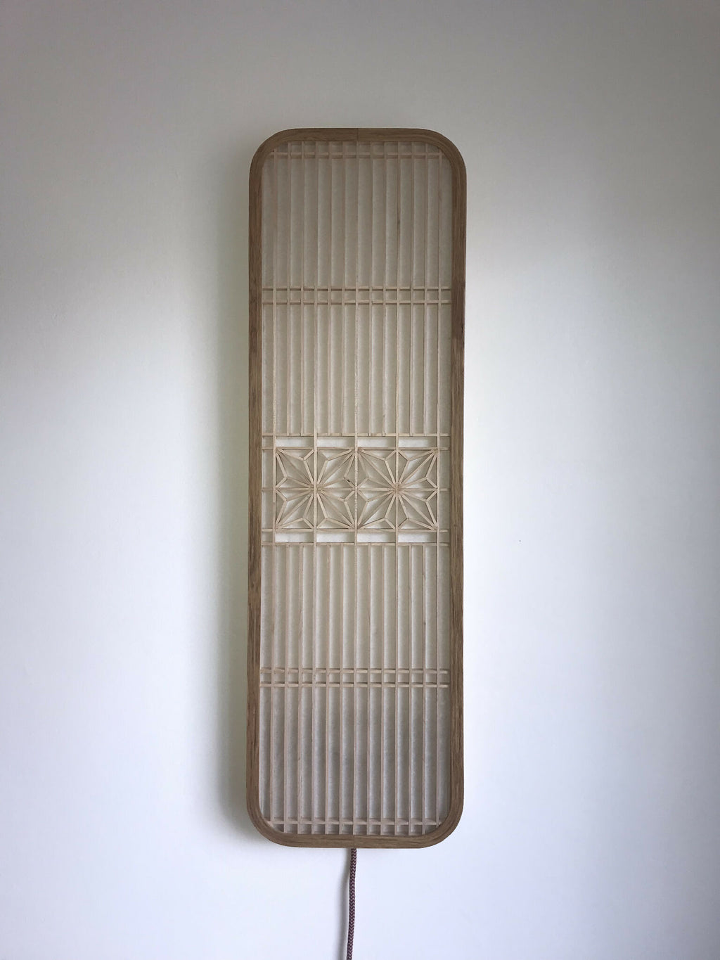 Décoration murale lumineuse Hotaru, cadre beige arrondi, rayures verticales et motif en bas.