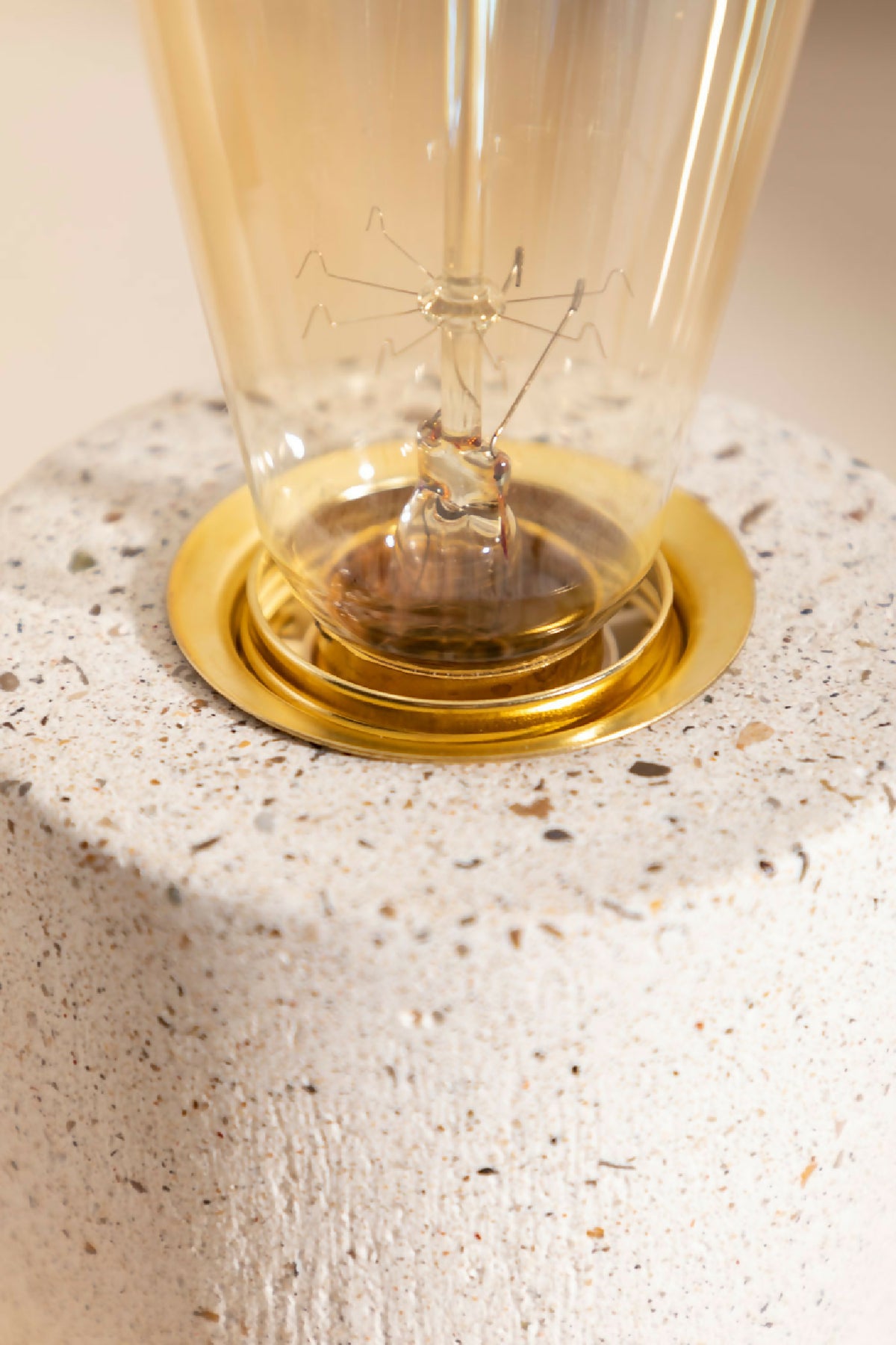 Socle rond beige clair texturé avec base dorée et ampoule en verre de lampe à poser