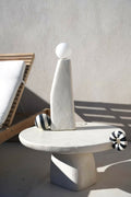 Sculpture lumineuse blanche sur base ovale, sphère au sommet et boules rayées sur le côté.