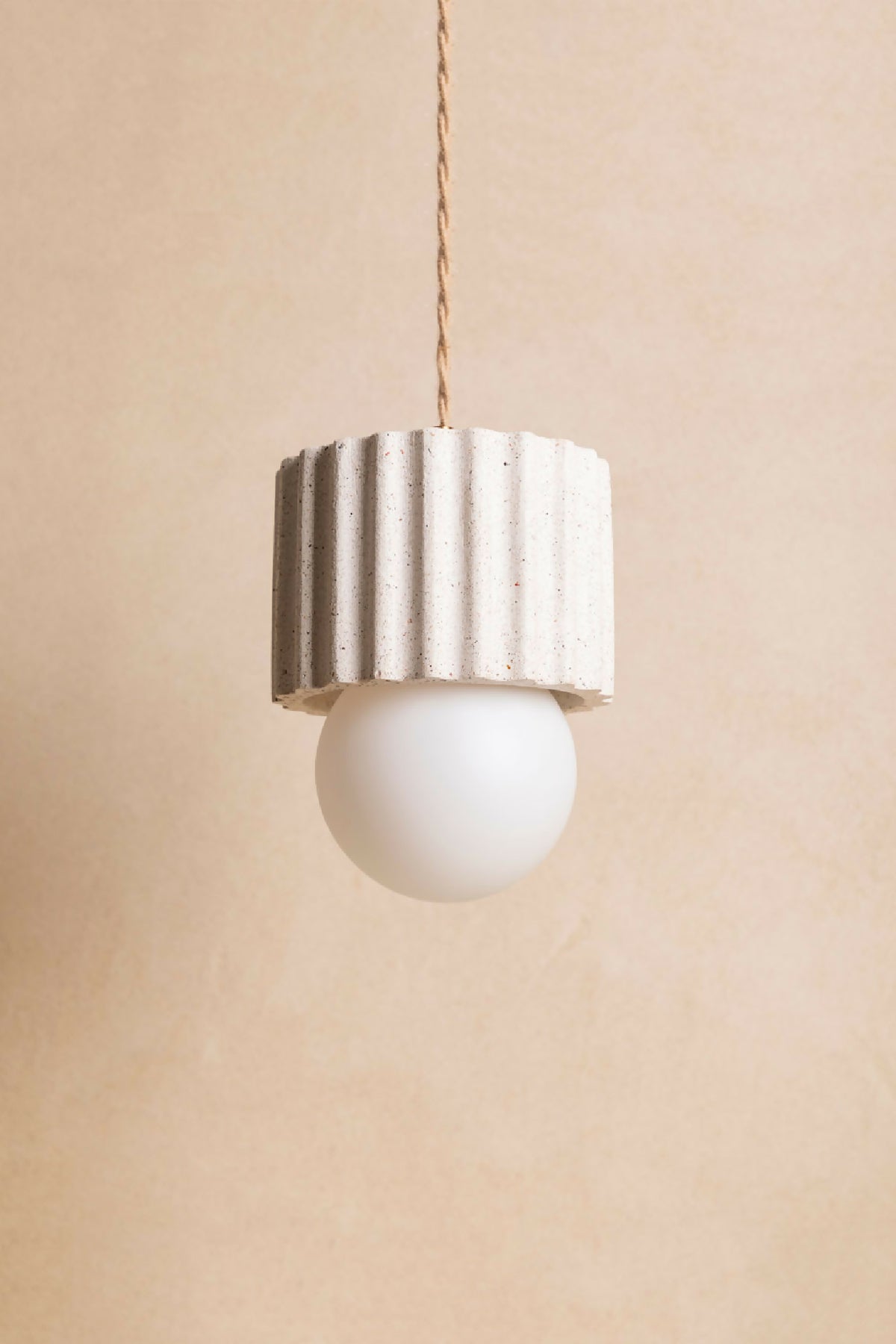 Suspension ILONA à abat-jour cylindrique blanc texturé, avec ampoule ronde blanche.