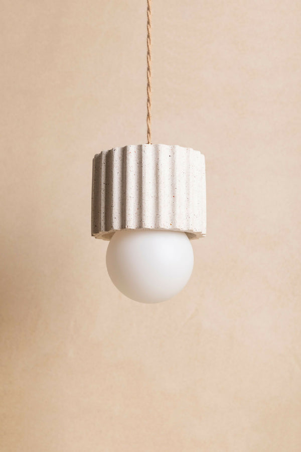 Suspension ILONA à abat-jour cylindrique blanc texturé, avec ampoule ronde blanche.