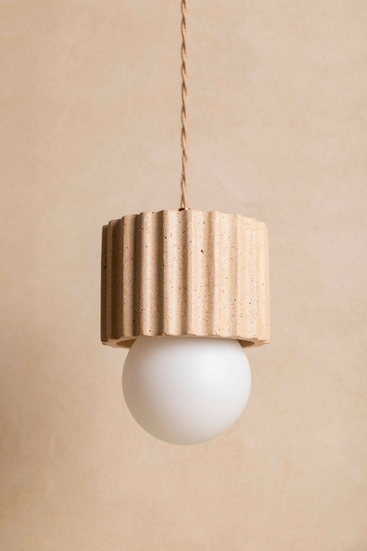 Suspension ILONA à abat-jour cylindrique beige texturé, avec ampoule ronde blanche.