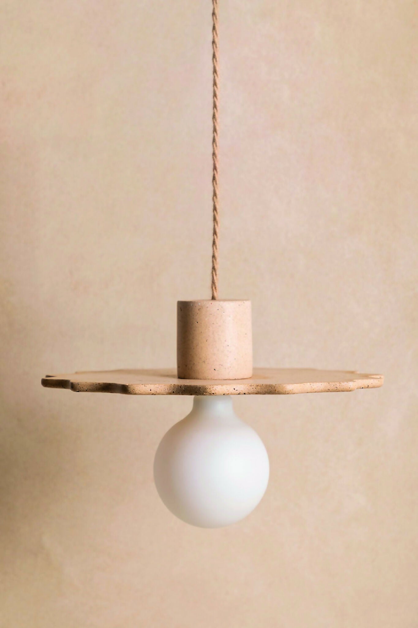 Suspension au diffuseur sphérique blanc, plateau ajouré en métal texturé sable.