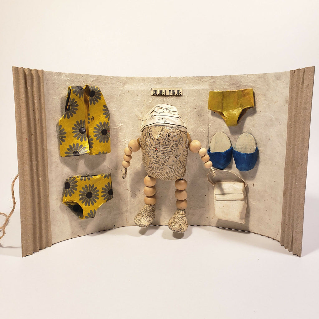Sculpture Coquet minois : figurine en tissu sur fond en carton avec accessoires bleus