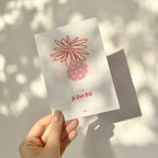 Carte de vœux blanche « Ma Bombe » tenue en main, illustration rouge et texte