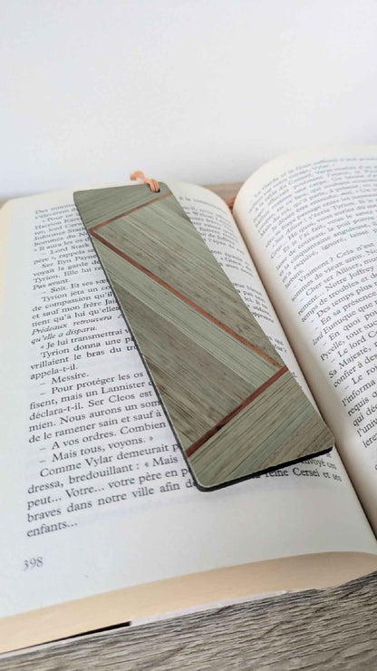 Marque-page en marqueterie de paille kaki, beige et touche cuivrée, sur livre ouvert