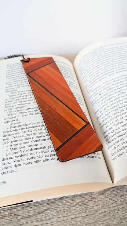 Marque-page en marqueterie de paille orange à lignes, posé sur un livre ouvert