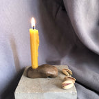 Mini bougeoir sur socle en pierre grise avec bougie jaune, coquillage et galets.