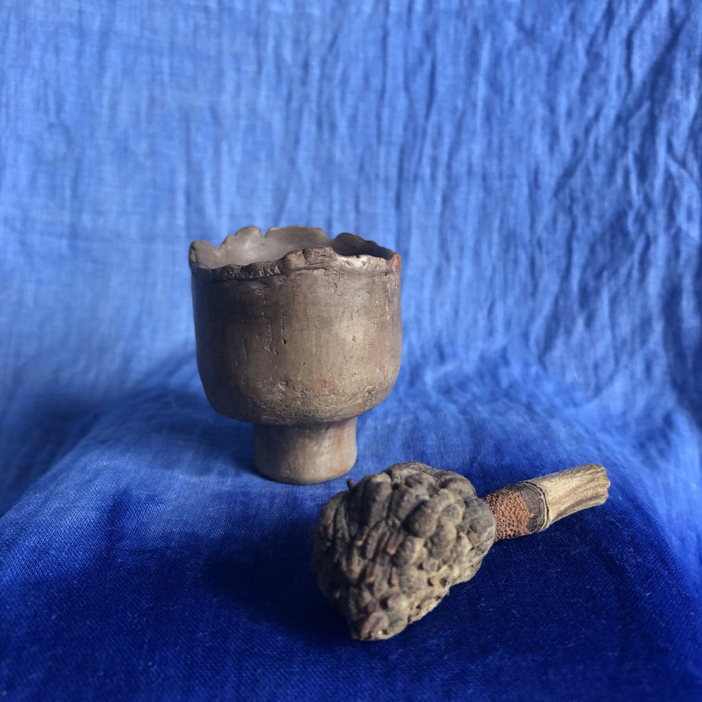 Petit pot en terre cuite sombre avec petite pièce sculptée à côté
