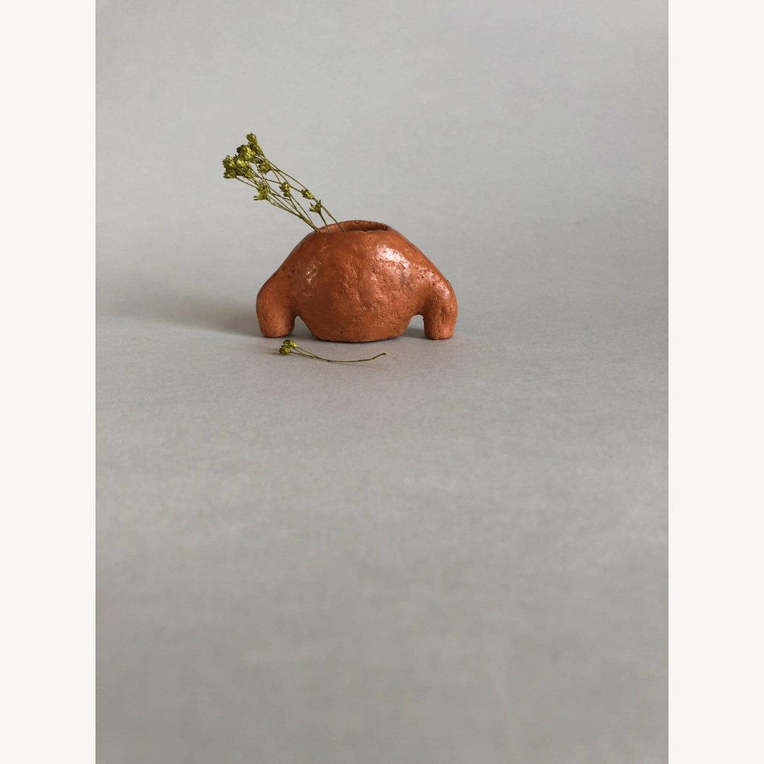 Petit vase en céramique brun cuivré, vue de profil avec tige d’herbe sèche.