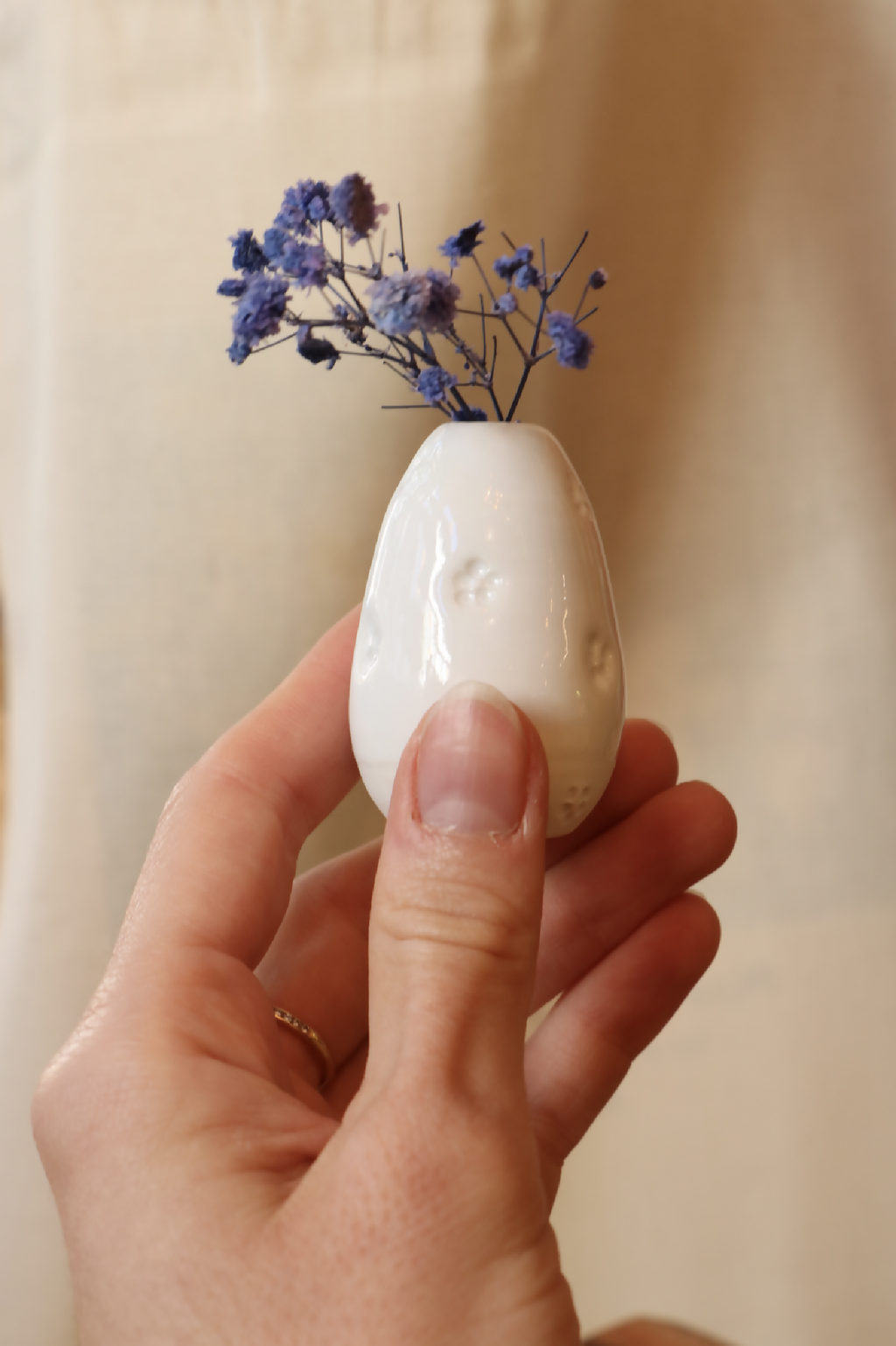 Mini-vase en porcelaine blanc, forme goutte, motif en relief, tenu à la main