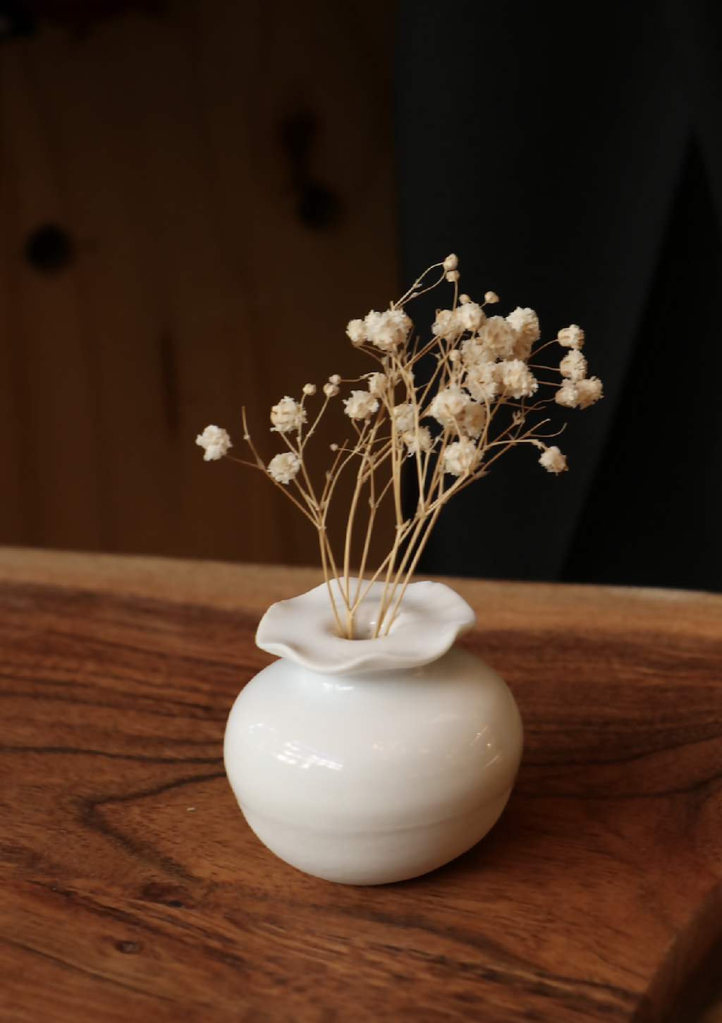 Mini-vase en porcelaine blanche sur table, fleurs séchées dans une petite urne