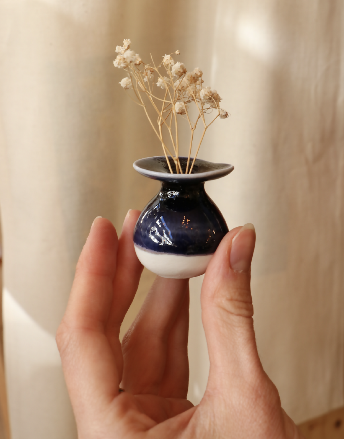 Mini-vase en porcelaine bleu foncé et blanc, tenu dans les mains