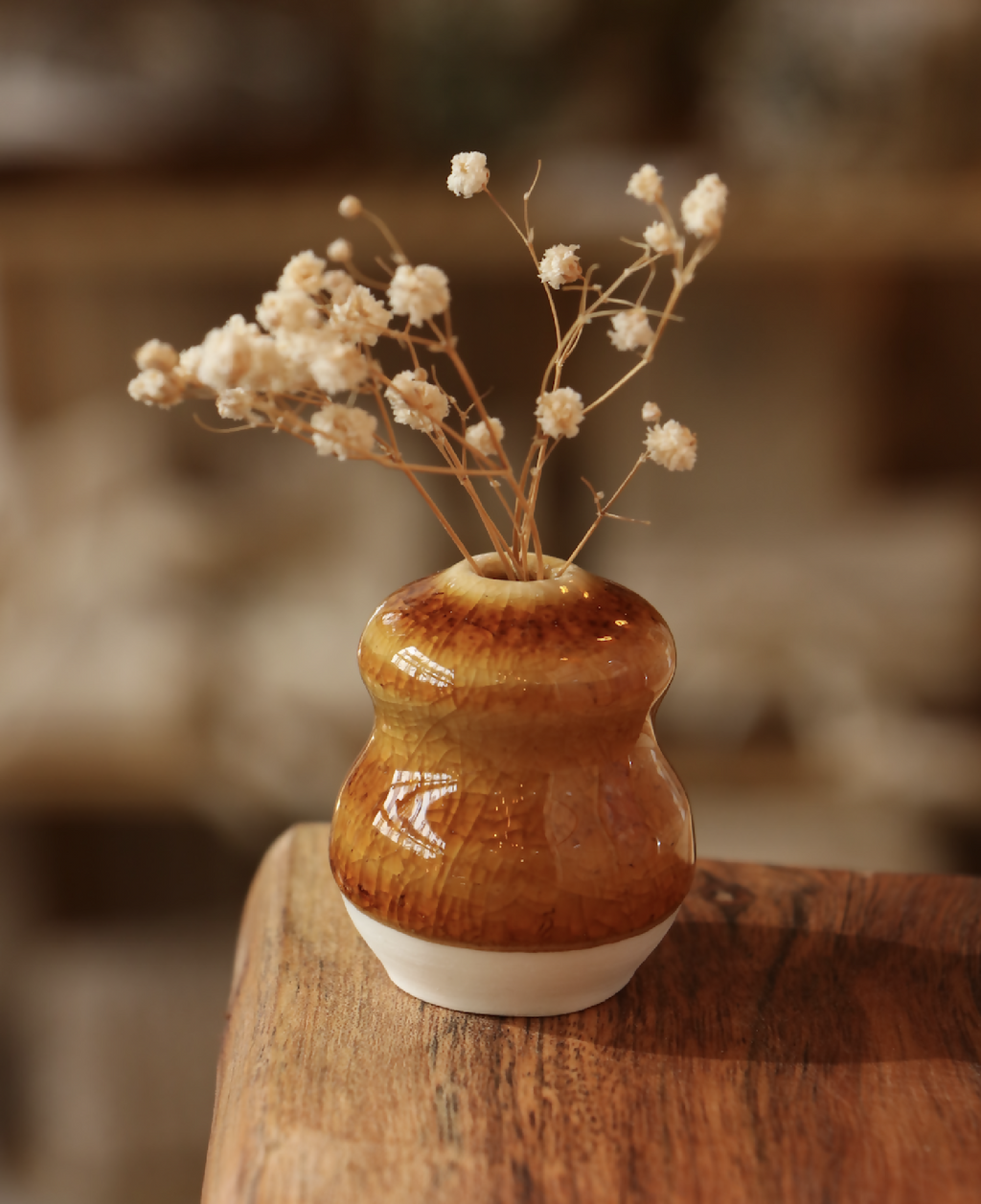 Mini-vase en porcelaine brun craquelé avec bord blanc, sur table en bois