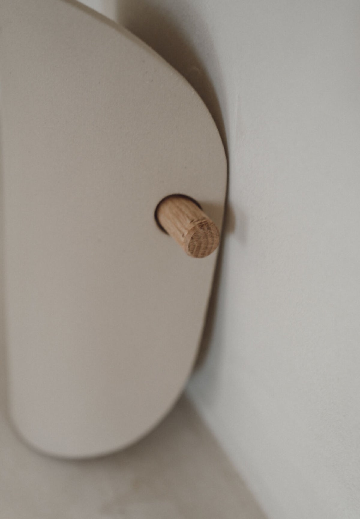 Détail fixation d’applique murale en céramique beige avec bouton en bois