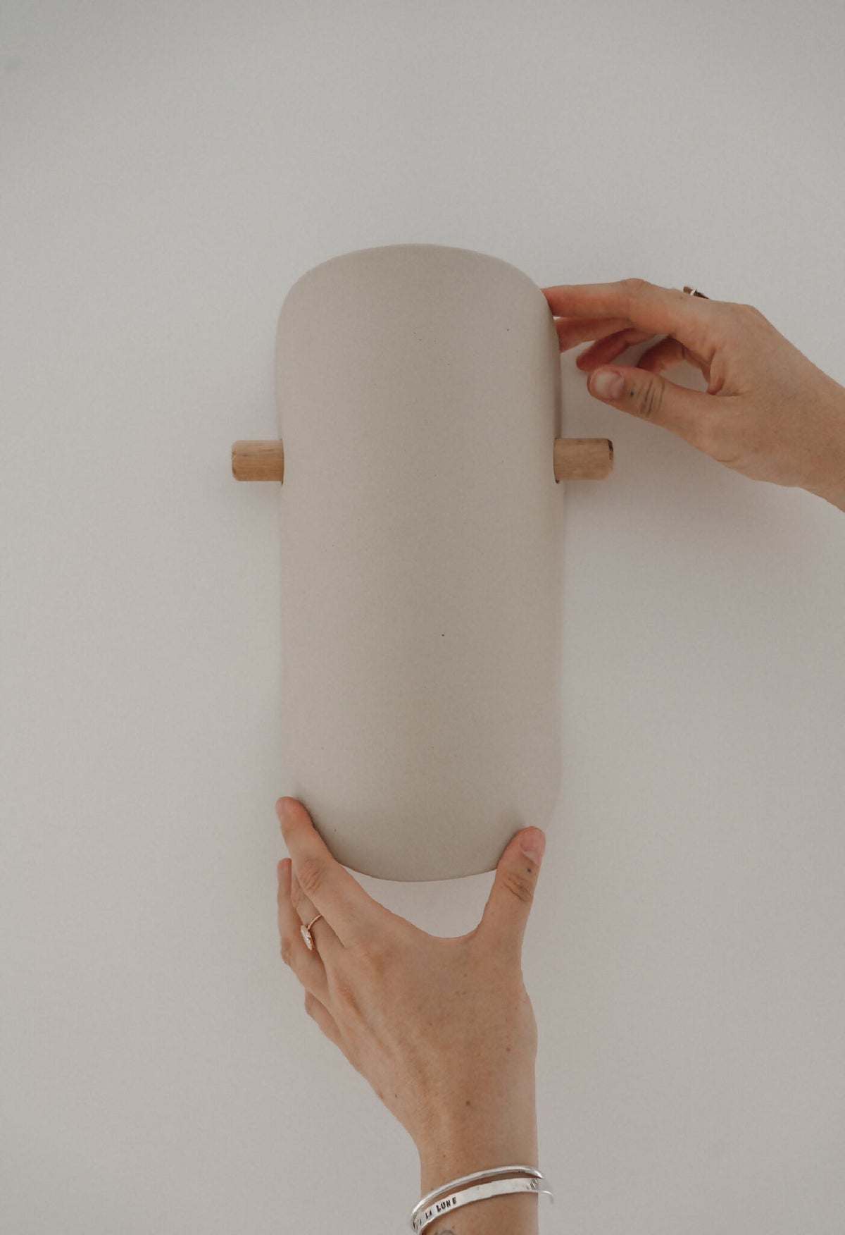 Applique murale en céramique beige, fixation par deux tiges en bois