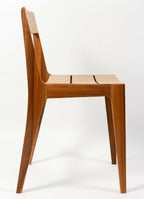 Chaise en bois brun foncé, dossier ajouré et assise plate, pieds légèrement évasés.