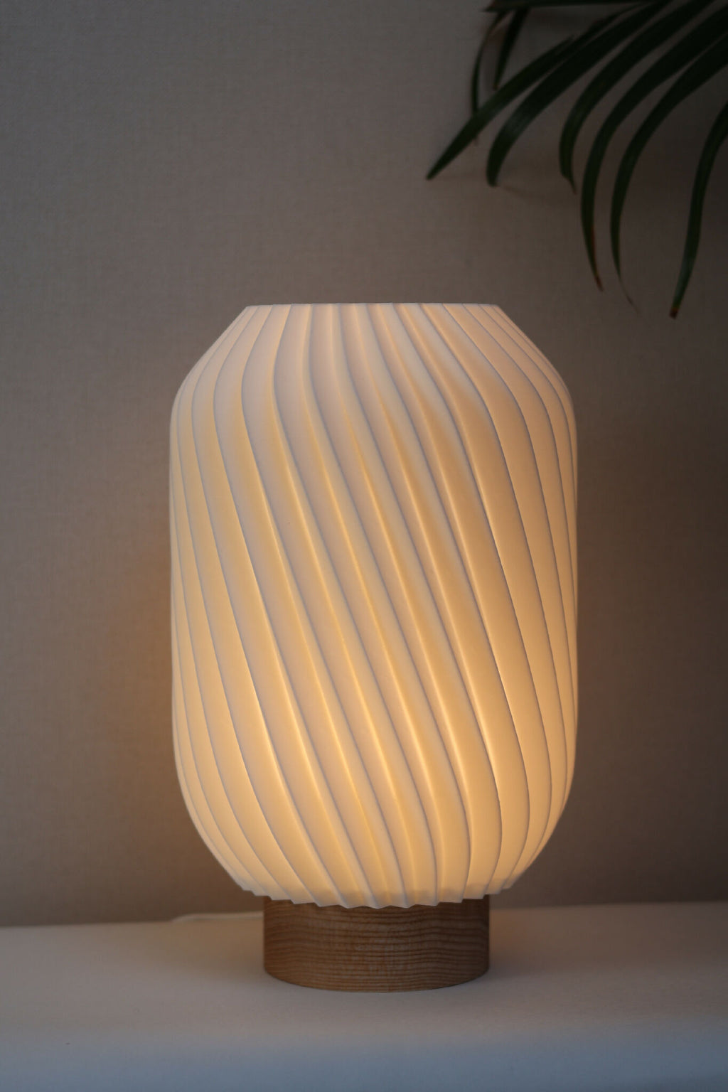 Lampe Orion abat-jour blanc strié, éclairée, sur base en bois