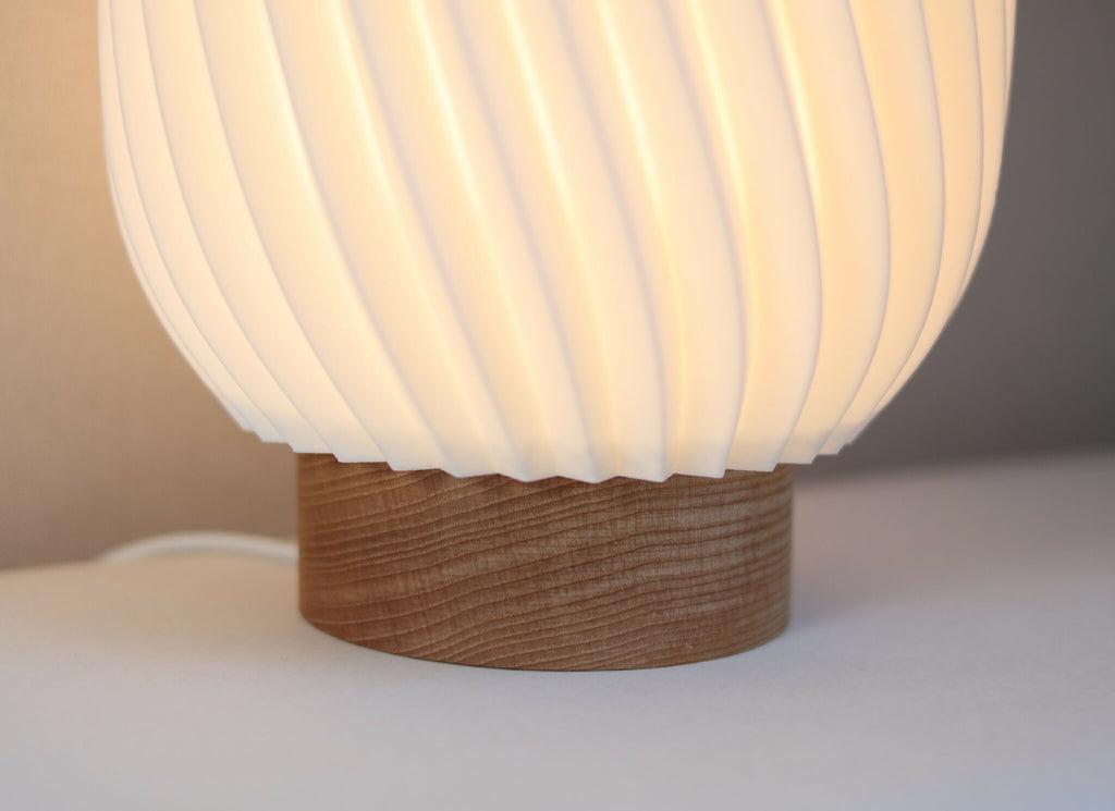 Lampe Orion abat-jour blanc strié, base en bois, vue de trois-quarts