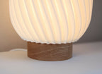 Lampe Orion abat-jour blanc strié, base en bois, vue de trois-quarts