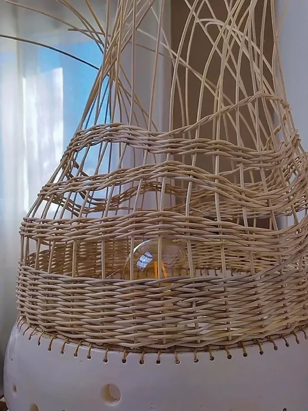Lampe à poser en tressage beige, abat-jour en cloche avec brins décoratifs.