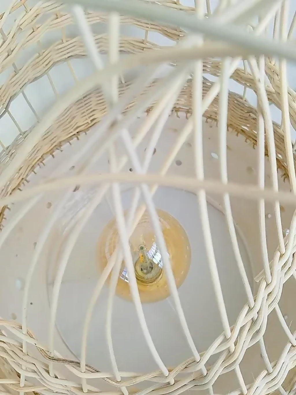 Lampe à poser en tressage blanc, ampoule centrale visible à travers l’abat-jour.