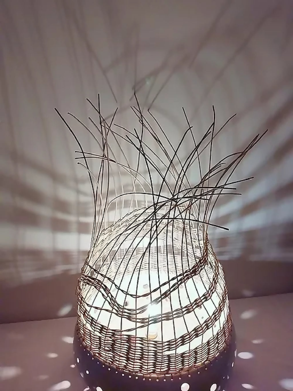 Lampe à poser en tressage sombre, base blanche à pois, fibres verticales au sommet.