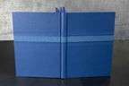 Livre d’or bleu, couverture ouverte avec un ruban de marque-page et des pages.