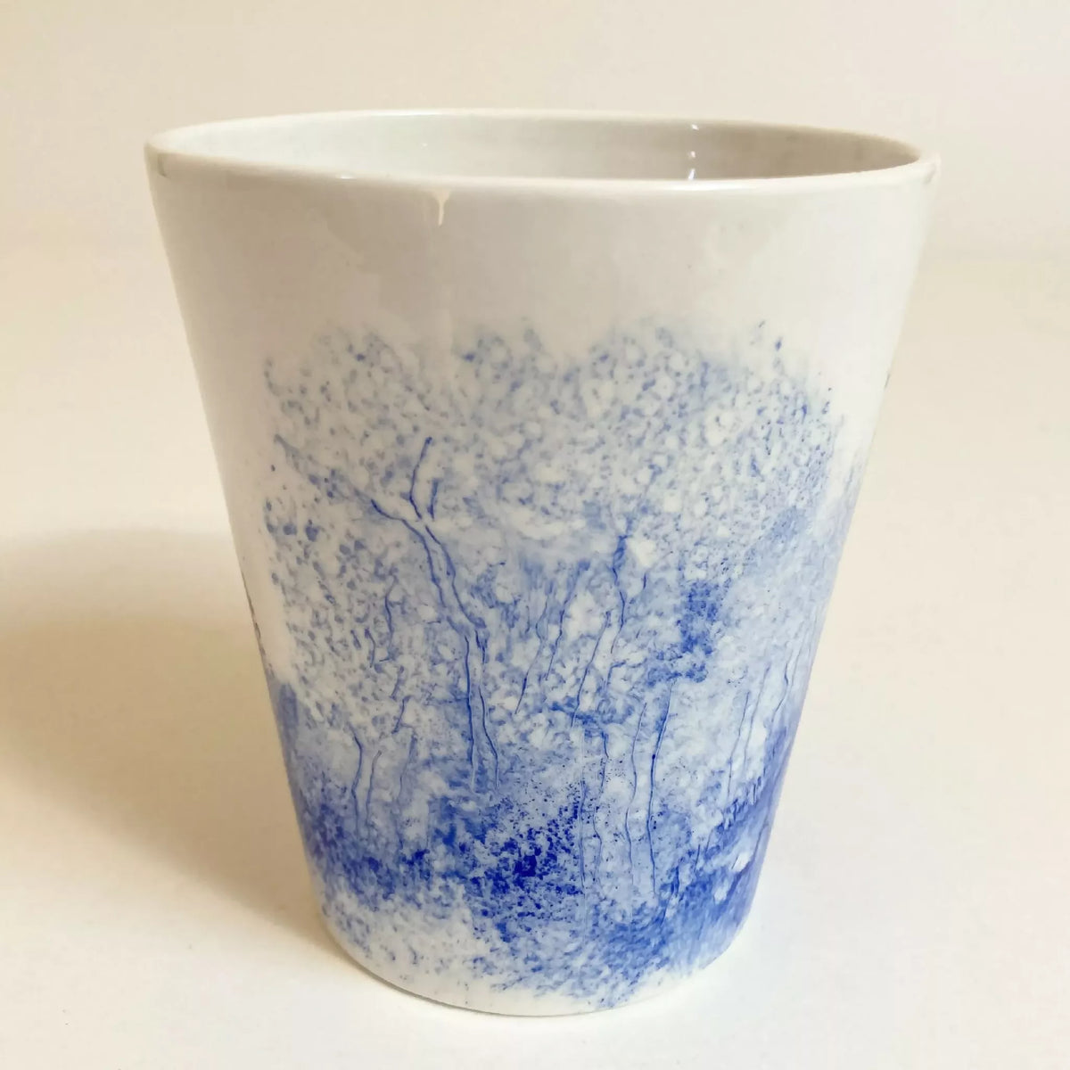Mug en céramique blanc, vue de face avec paysage bleu et tracés d’arbres