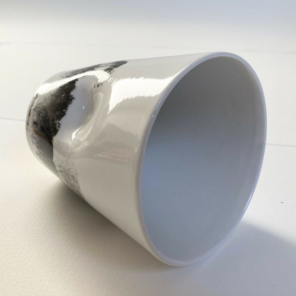 Mug en porcelaine blanc, vue latérale, intérieur clair et décor paysage noir