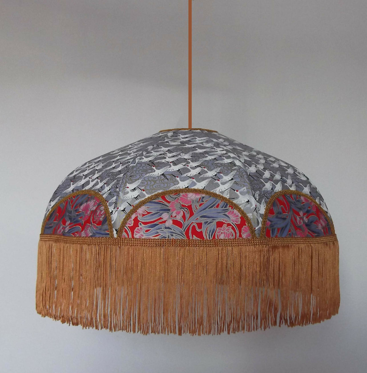 Suspension rétro avec abat-jour arrondi gris, motifs japonais et franges dorées.