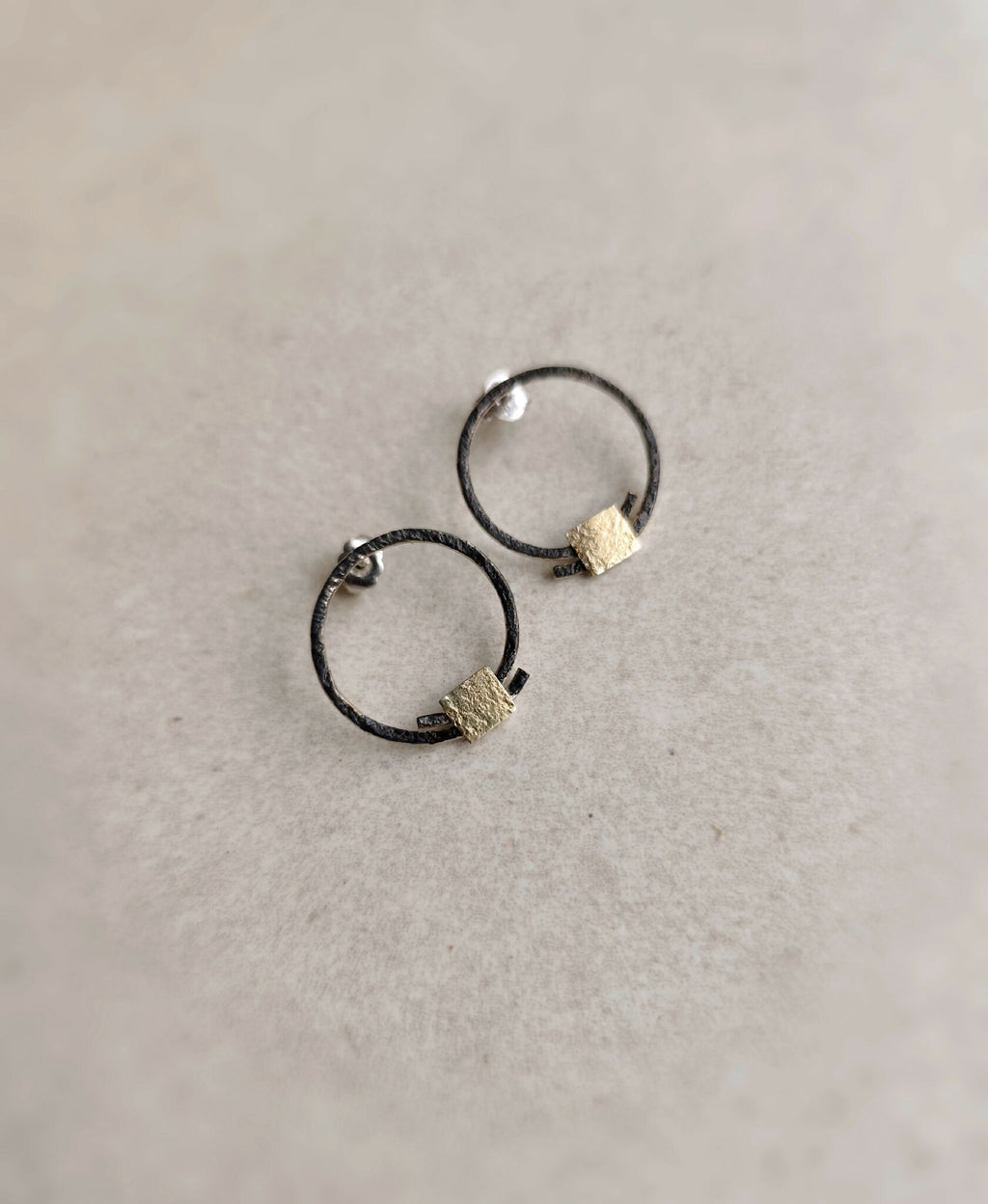Boucles d’oreilles anneaux noirs, carrés texturés dorés, vue de dessus