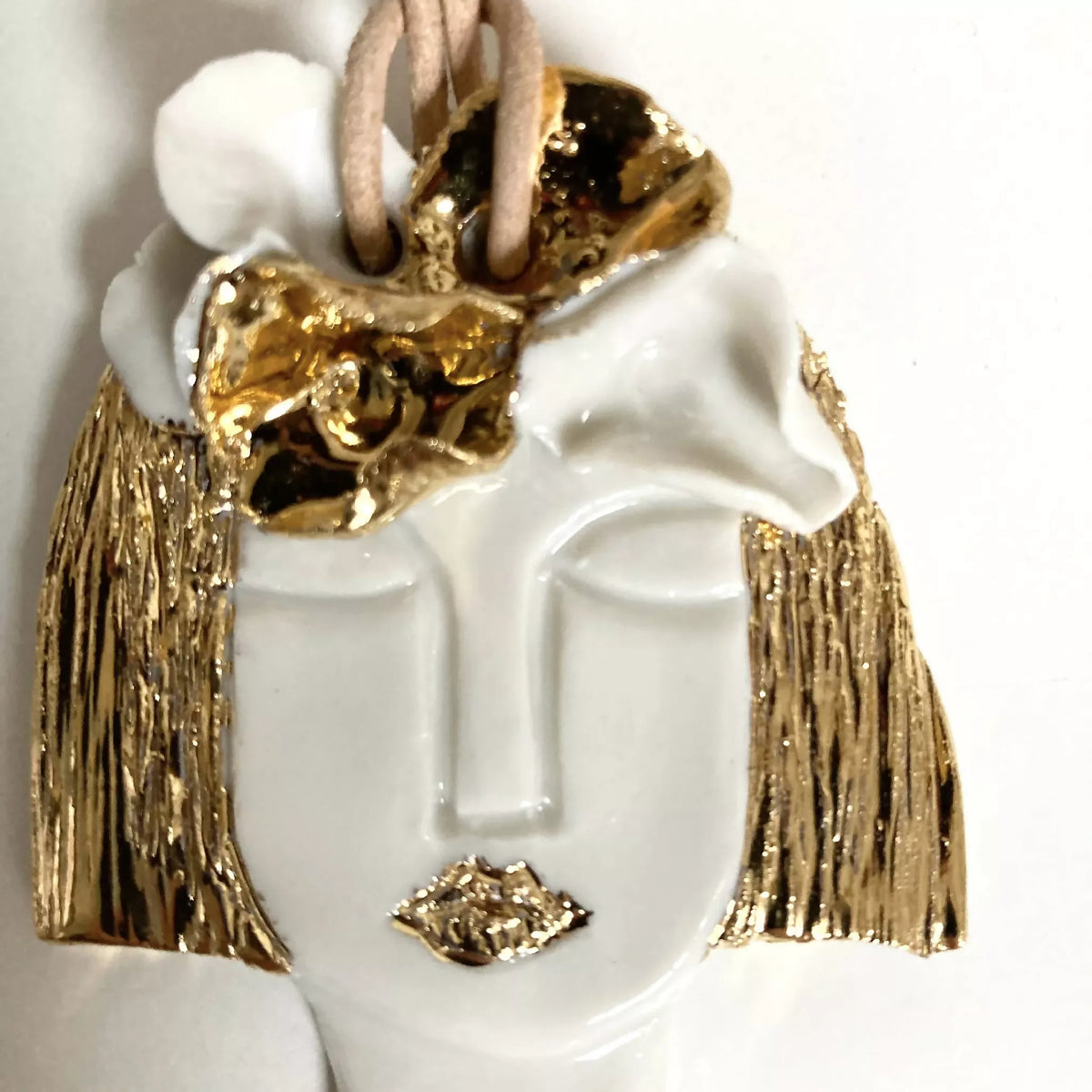 Pendentif buste blanc avec visage doré en relief, col clouté et franges or