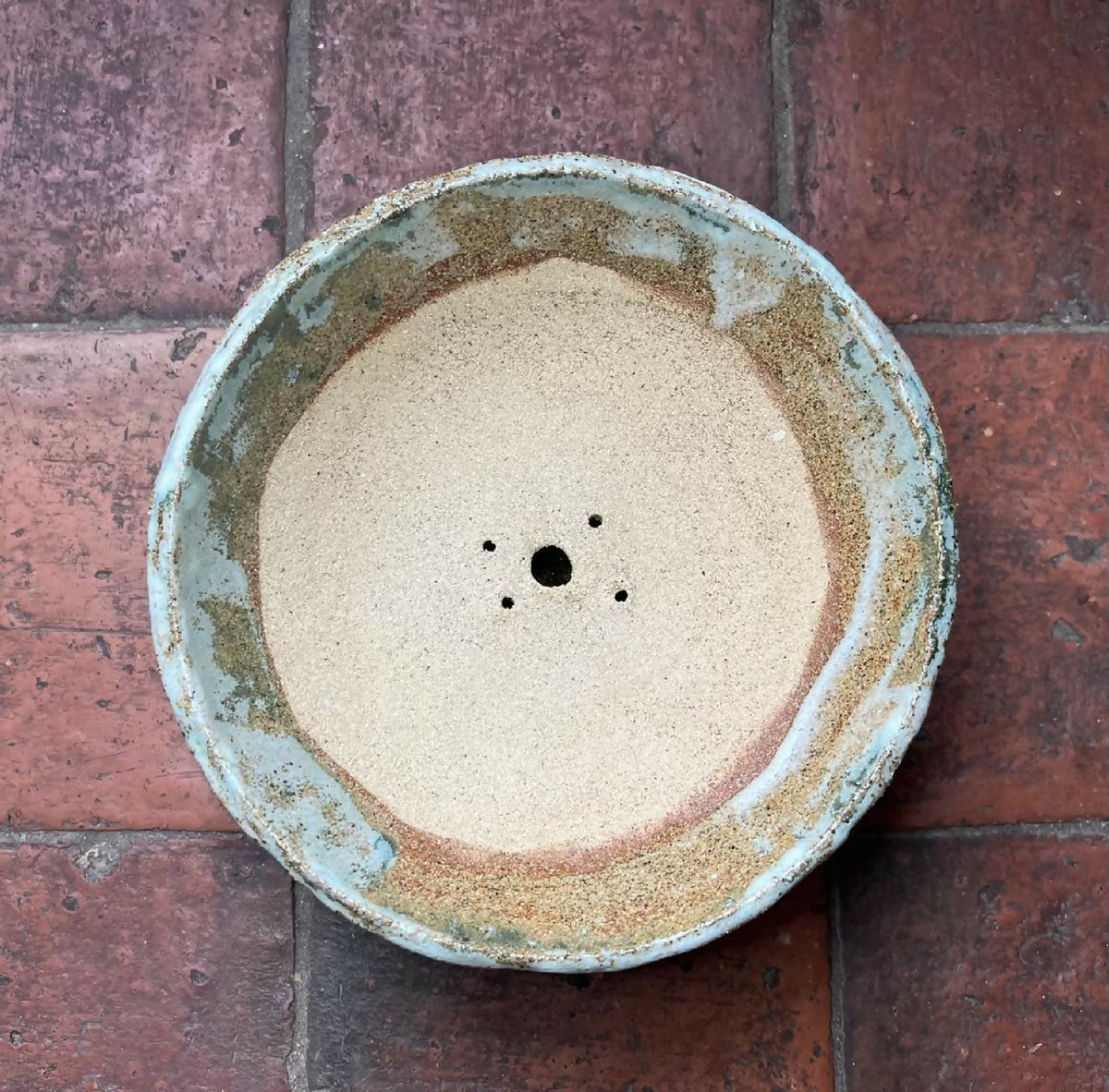 Dessous d’un grand pot rond pour bonsaï en céramique bleu-gris, trous centraux