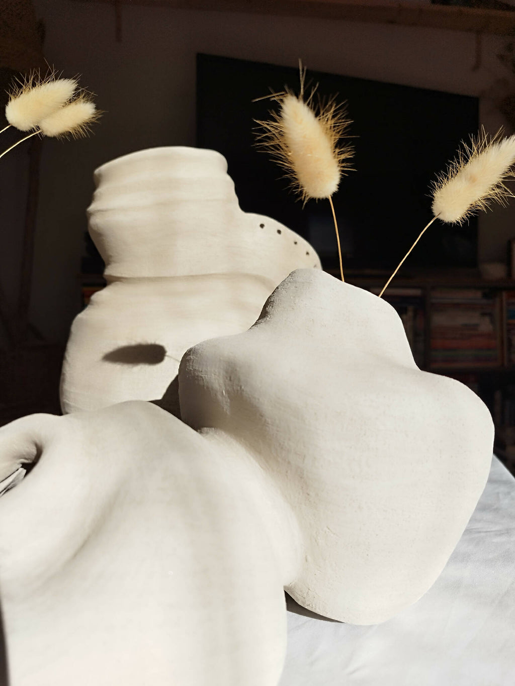 Peluche décorative blanche avec museau arrondi et oreilles, touffes beige sur cordelettes.