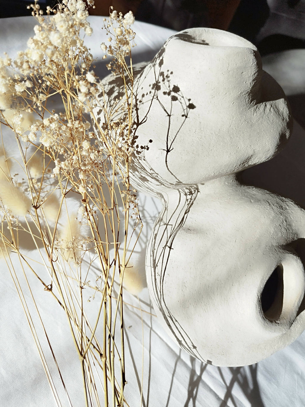 Peluche décorative blanche orientée sur le côté, avec petites touffes beige et bouquet décoratif.