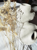 Peluche décorative blanche orientée sur le côté, avec petites touffes beige et bouquet décoratif.