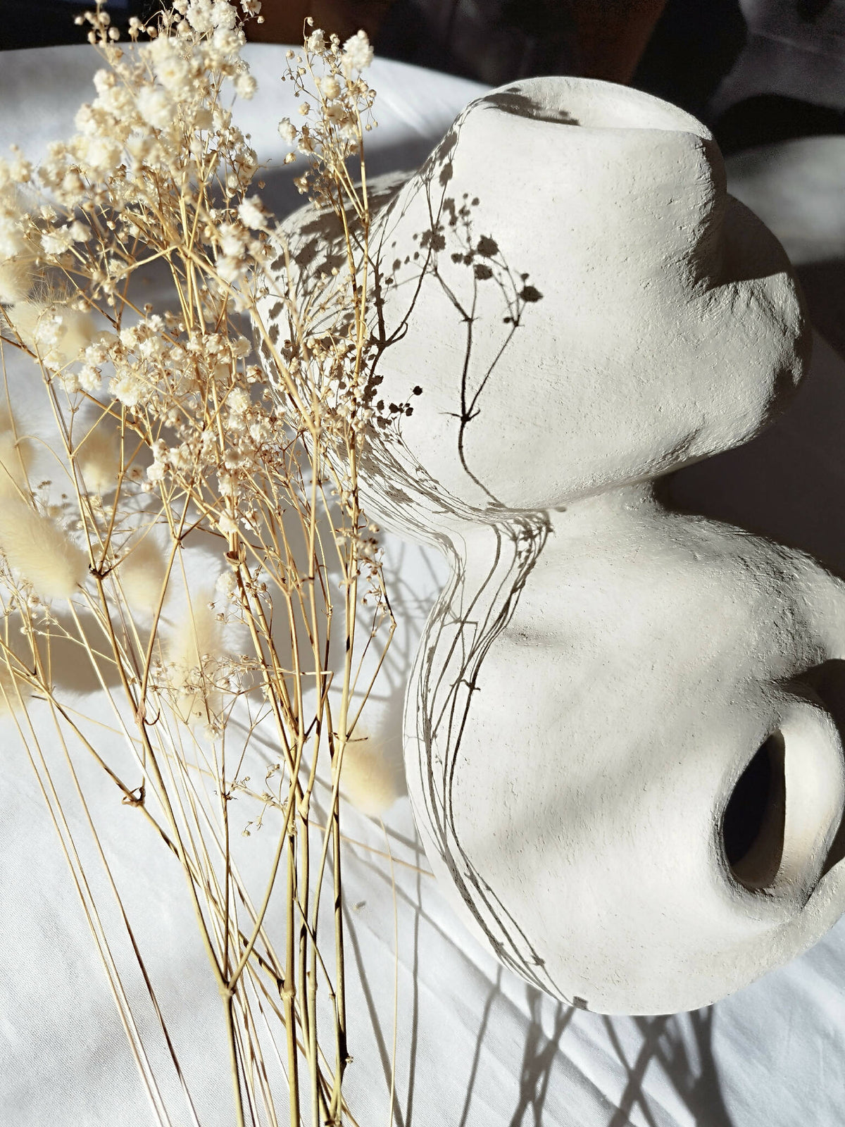 Peluche décorative blanche orientée sur le côté, avec petites touffes beige et bouquet décoratif.