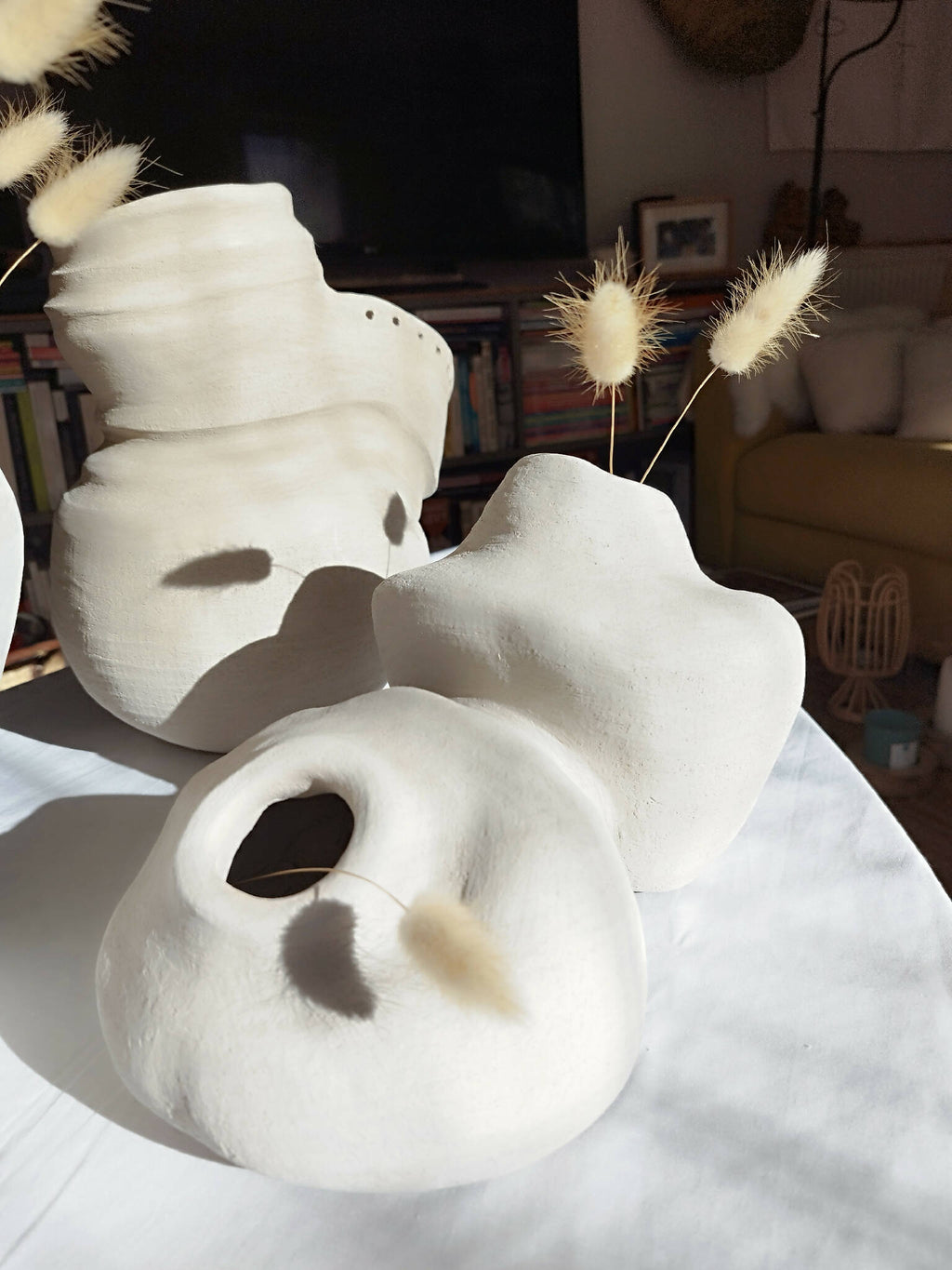 Peluche décorative blanche en forme d’animal, profil avec oreilles et museau en relief.