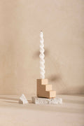 Bougeoir à bougie torsadée blanche, base beige en blocs carrés sur socle texturé