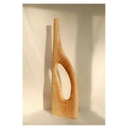 Objet décoratif en bois blond avec forme incurvée et ouverture en U.