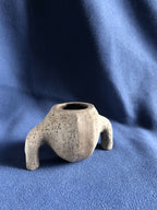 Petit pot en pierre gris clair, forme irrégulière, deux supports latéraux, ouverture.