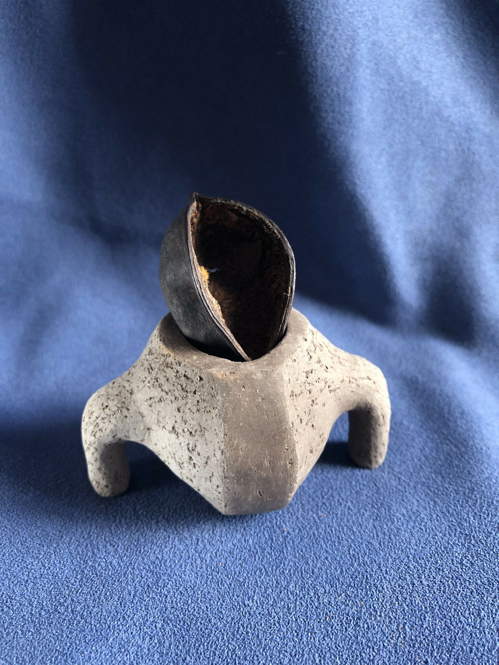Petit pot en pierre gris avec ouverture ronde, intérieur sombre et bords irréguliers.