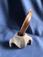 Petit pot en pierre grise avec tige en bois insérée dans l’ouverture.