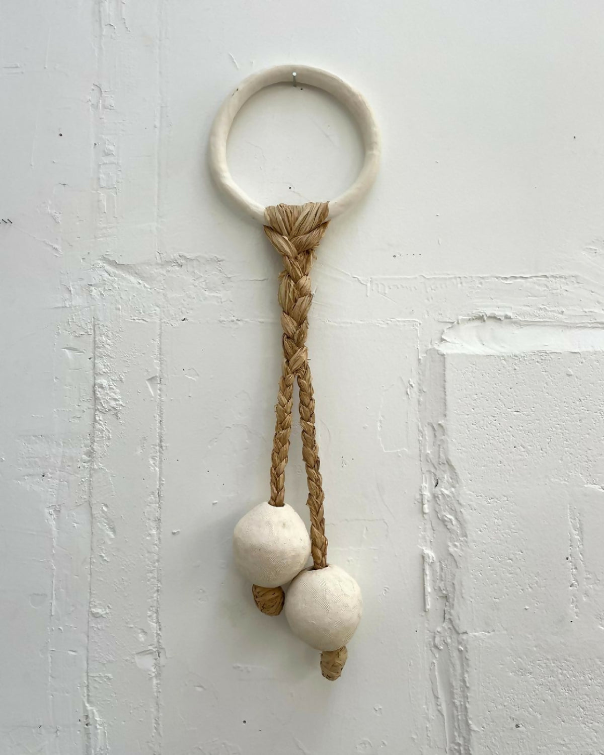 Décoration murale avec anneau en bois clair et cordelettes torsadées beige